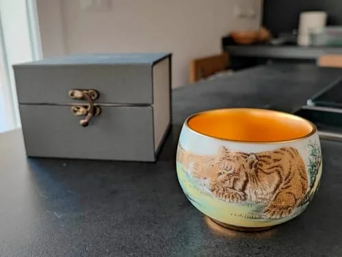 Customer's The Tiger bowl with its detailed tiger illustration and golden interior, sitting on a counter next to its grey box.