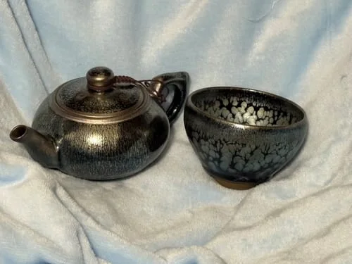 Customer's Nebula teacup with a dark speckled glaze, shown next to a complementary teapot.