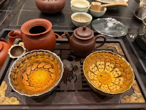 Customer's two Vivid Lotus tea cups with vibrant interior patterns on a dark wood tea tray, one filled with tea.